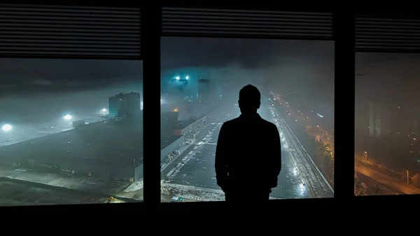 The lonely man standing near the window on the rainy background