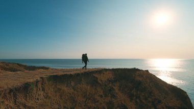 Güzel gün batımına karşı bir dağda yürüyen yürüyüşçü