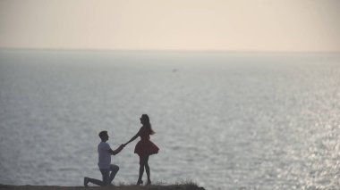 Adam deniz manzaralı kadına evlenme teklif ediyor.