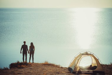 Erkek ve kadın deniz kenarındaki kamp alanında dinleniyorlar.