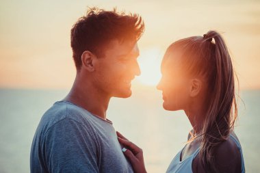 Romantik çift güzel günbatımı arka planında yakın duruyor.