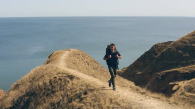 Deniz kenarındaki sıradağlarda yürüyen bir turist.