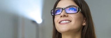 Projektörün arka planında gözlüklü mutlu iş kadını.