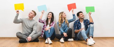 Dört mutlu arkadaş beyaz arkaplanda diyalog işaretleri tutuyor