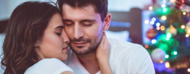 Güzel çift Noel ağacının yanında oturuyor.