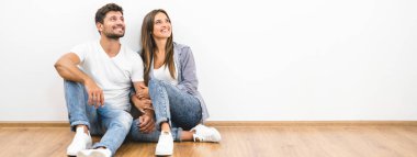 Mutlu çift beyaz duvarın arkasında oturuyor.