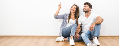 Mutlu adam ve kadın beyaz duvarın arkasında oturuyor.