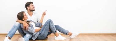 Gülümseme çift oturmak ve beyaz duvar arka plan üzerinde jest