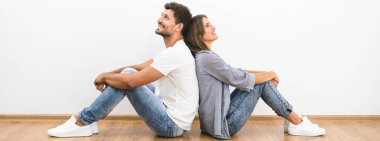 Gülümseyen adam ve kadın boş duvarın arkasında oturuyor.