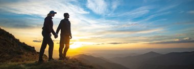 Kayanın üzerinde duran çift, güzel bir gündoğumuyla