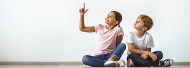 Mutlu kız ve bir oğlan yerde oturup el kol hareketi yapıyorlar.