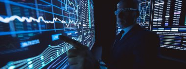 Karanlık laboratuardaki büyük sensör ekranında çalışan adam.