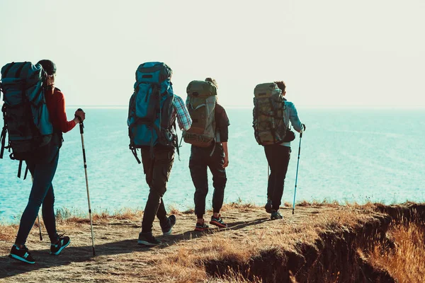 Четыре Туриста Рюкзаками Прогуливаются Вдоль Морского Берега — стоковое фото
