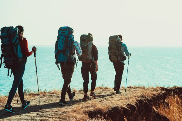 Empat Wisatawan Dengan Ransel Berjalan Sepanjang Pantai Laut — Stok Foto