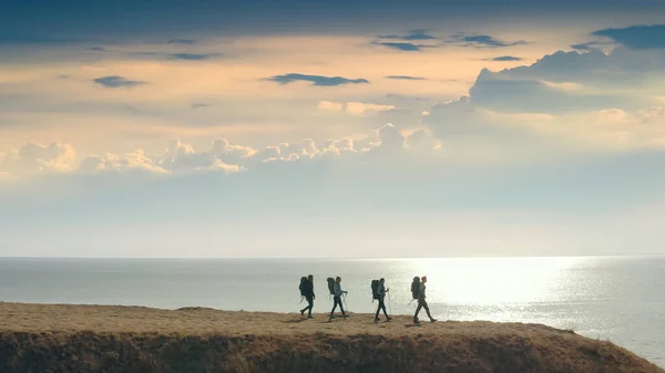 Neljän Ihmisen Ryhmä Kävelee Vuoren Reunalle Lähellä Merta — kuvapankkivalokuva