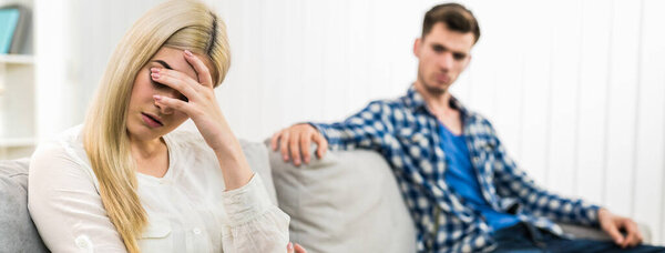 Грустная женщина сидит рядом с мужчиной на диване
