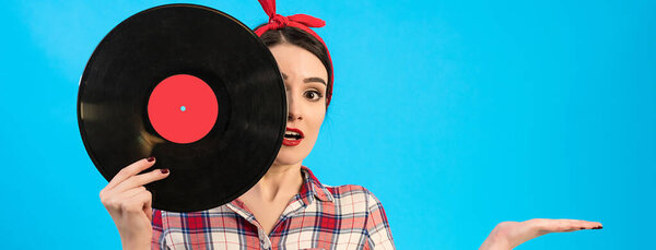 The surprised woman holding a vinyl record on the blue background
