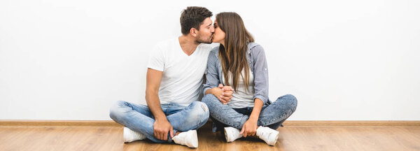 Счастливый мужчина и женщина целуются у пустой стены