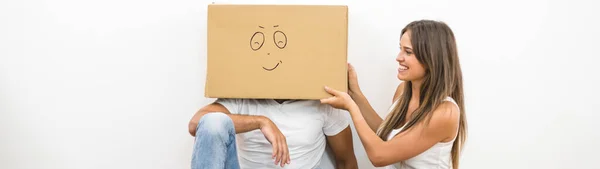 这个快乐的女人坐在男人身边 头上顶着一个纸盒 — 图库照片