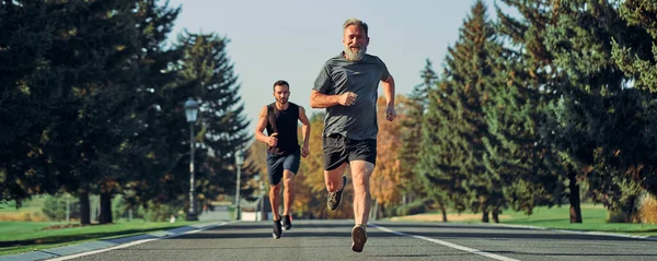 The old and young sportsmen running on the road