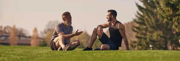 The father and son sitting on the grass and talking