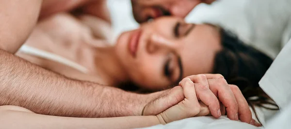 Tutkulu adam ve kadın yatakta oynuyorlar.