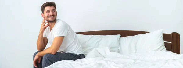 Homem Feliz Sentado Cama Fundo Branco — Fotografia de Stock