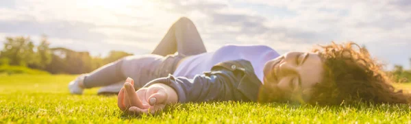 Mutlu kadın çimenlerin üzerine uzandı. Güneşin arka planında.