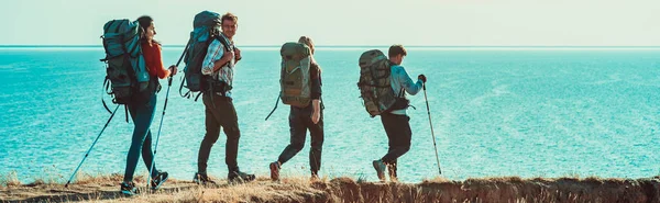 Empat Wisatawan Dengan Ransel Berjalan Sepanjang Pantai Laut — Stok Foto