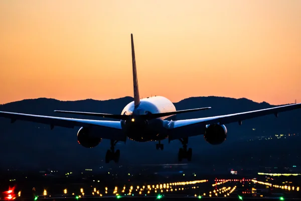 Avión aterrizando al aeropuerto al anochecer — Foto de Stock