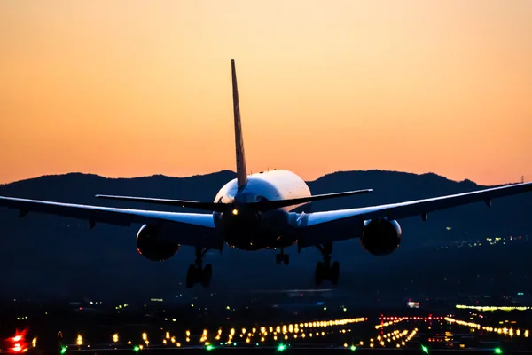 飞机降落到机场在黄昏 免版税图库照片