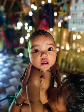 Bandarban, Bangladeş 'teki bir tepe köyünde bir kabile evinden hayretle kameraya bakan küçük bebek. Kameradaki küçük kız.