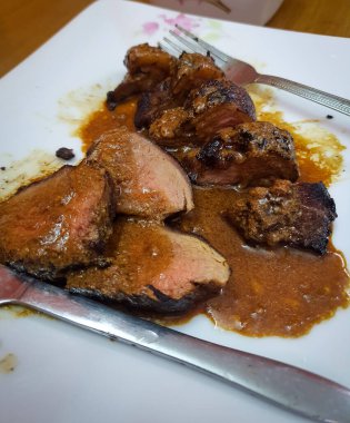 Lezzetli sarımsaklı biftek soslu orta pişmiş sığır filetosu. Biftek tabakta servis edilir.