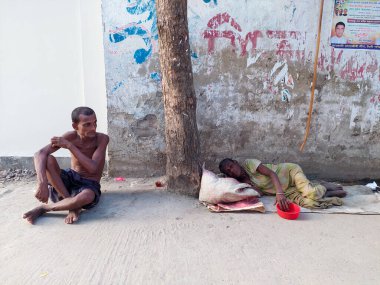 Dhaka, Bangladeş - 11.07.2021: Bangladeş 'te korona kilitlenirken işsiz ve aç insanlar bir demiryolunda oturup dileniyorlar. Corona kapanması sırasında yoksulluk ve kriz