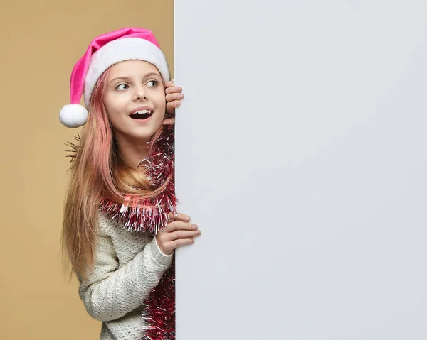 Noel Baba şapkalı tatlı kız, mesaj için şaşırmış görünüyor. Noel ve yeni yıl reklam konsepti