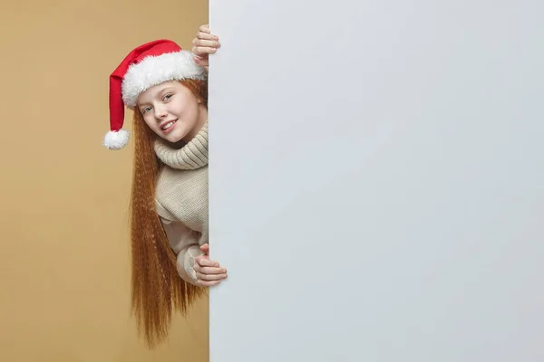 Vrolijk Roodharig Meisje Een Kerstmuts Met Een Wit Billboard Waarop — Stockfoto