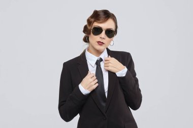 Eski moda saç stili olan çekici bir kadın erkek kıyafeti ve güneş gözlüğü takıyor.