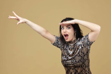 Çekici esmer kadın elini çeker ve kameraya hayretle bakar.