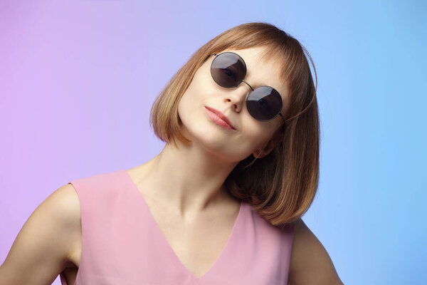 stylish girl in sunglasses. photo shoot in the studio on a pink background