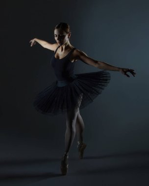 Çekici balerin siyah arka planda stüdyoda zarifçe poz veriyor.