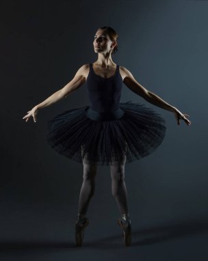 Çekici balerin siyah arka planda stüdyoda zarifçe poz veriyor.