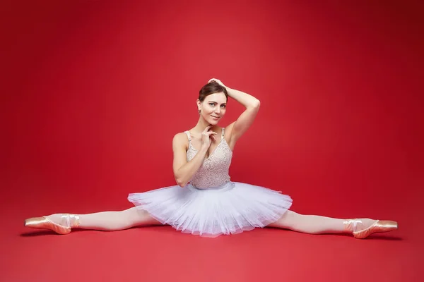 Vacker Ballerina Satte Sig Ner Splittringen Fotografering Studion Röd Bakgrund — Stockfoto