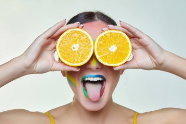 parlak dudakları olan çekici bir kız, gözleri yerine portakal dilimlerini tutan.
