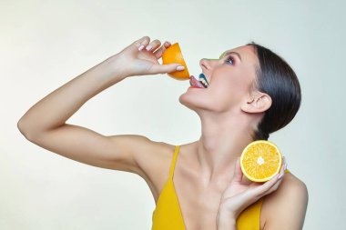 Çekici genç bir kadın dilini bir dilim portakala değdirdi.