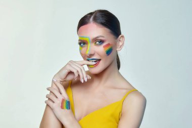 Parlak makyajlı çekici bir kızın portresi. Yanağında gökkuşağı LGBT bayrağı var.