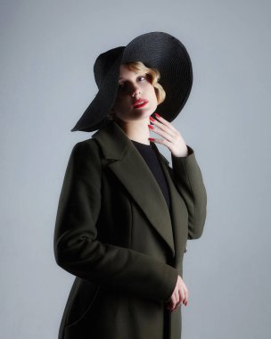 Eski moda saç stili, geniş kenarlı siyah şapkalı çekici bir sarışın.