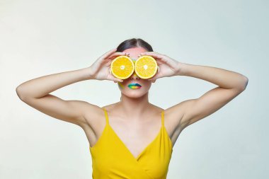 Çekici kız yüzünün önünde portakal dilimleri tutuyor.