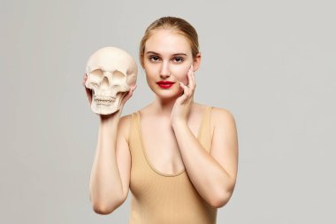 Çekici sarışın elinde bir kafatası tutuyor. Fotoğrafçılık kavramı kozmoloji, tıp ve sağlık alanında uygundur..