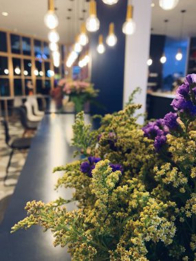 İç dizaynda bir buket çiçek. Güzel bir kafe için güzel bir dekorasyon. Lambalı sarı ve mor çiçekler