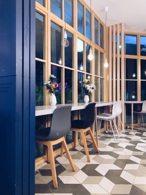 Samimi ve güzel bir kafe. Ahşap elementlerle dekorasyon, bir buket çiçek ve büyük pencereler. Güzel kafeteryaların tasarımında mavi ve beyaz sandalyeler